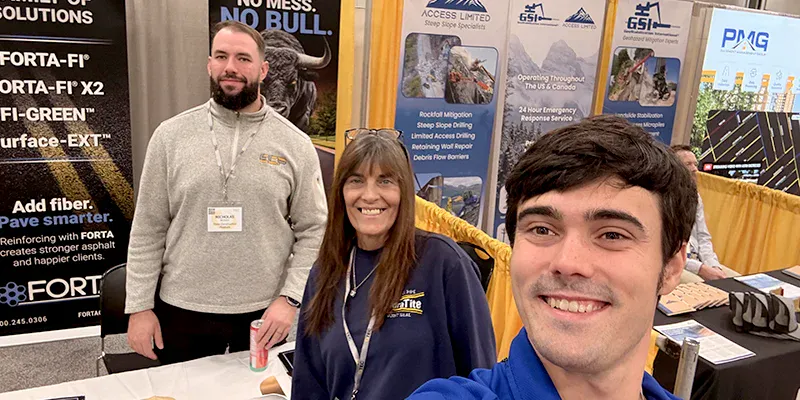 Three people standing in a booth at OTEC