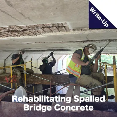 A group of people chipping away loose concrete on the underside of a bridge