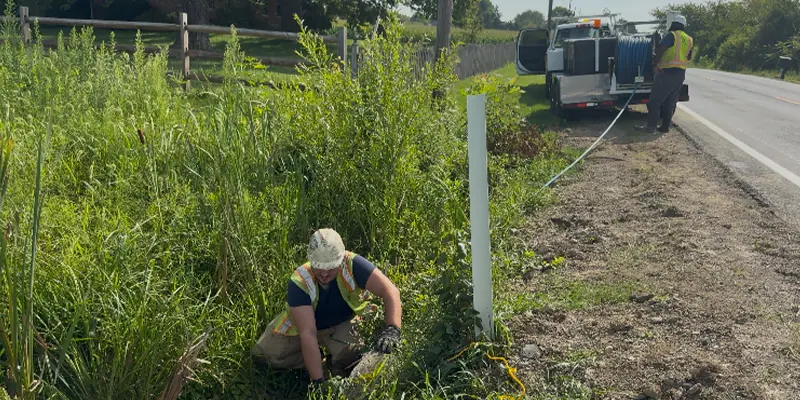 Two technicians working together to operate a jettervac to clear out a culvert
