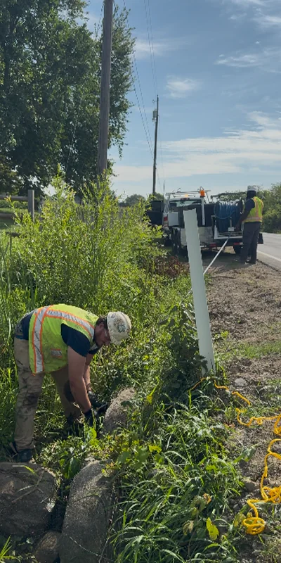 Two technicians working together to operate a jettervac to clear out a culvert