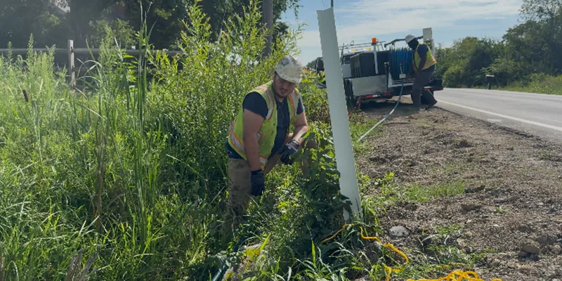 Two technicians working together to operate a jettervac to clear out a culvert