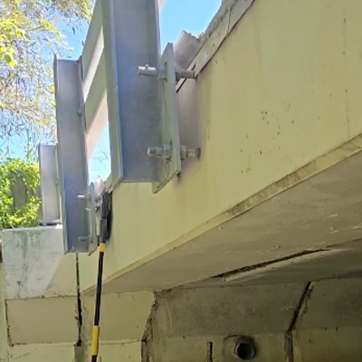 A broom being used to clean the side of a bridge